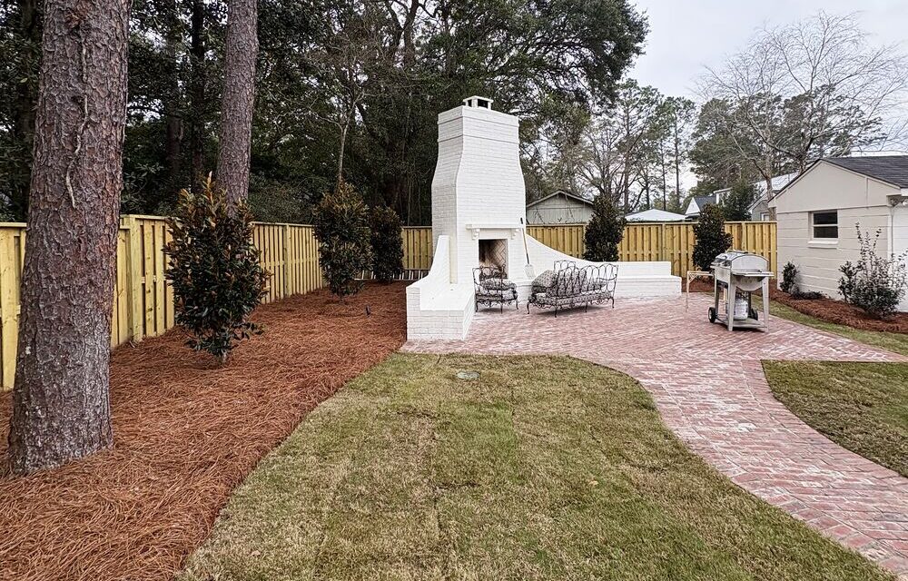 Renovated backyard with white outdoor fireplace, paver patio and fresh sod