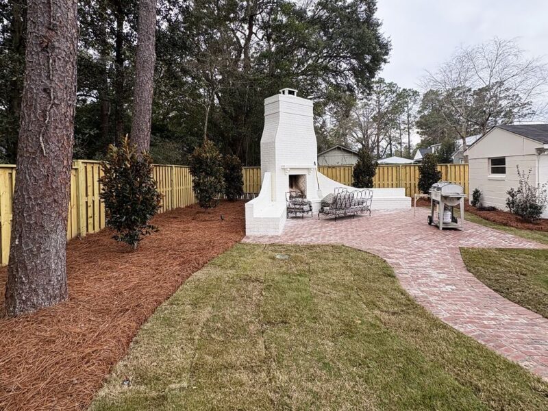 Renovated backyard with white outdoor fireplace, paver patio and fresh sod
