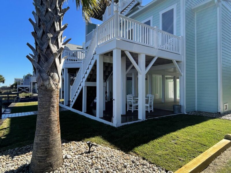 Palm tree in a river-rock bed with fresh sod at a Carolina beach home