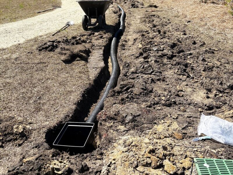 French drain installation with catch basin and corrugated pipe in an open trench